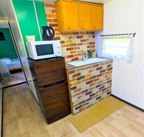 a kitchen with a microwave and a brick wall at BULLsキャンプ 富士の麓 自然に囲まれたペットと泊まれるゲストハウス Guesthouse with pets at the foot of World Heritage Mt Fuji in Fujikawaguchiko