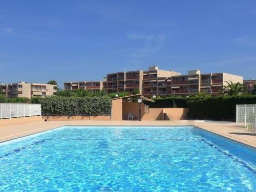 une grande piscine devant un immeuble dans l'établissement Appartement cosy 2 pièces avec piscine et tennis, proche plage à Bormes-les-Mimosas - FR-1-251-797, à Bormes-les-Mimosas