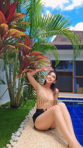 a woman in a bikini sitting next to a palm tree at Bali Villas Panglao Bohol in Panglao