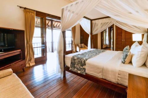 a bedroom with a canopy bed and a television at Majestic 3 BR Private Pool Villa NE18 in Jimbaran