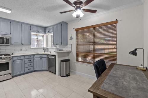 a kitchen with blue cabinets and a ceiling fan at The Charming House & Pool in DFW in Keller