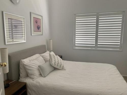 a bedroom with a bed with white sheets and two windows at Life's A Beach in Manyana