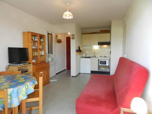 un salon avec un canapé rouge et une cuisine dans l'établissement Charmant T2 à Bormes-les-Mimosas, 4 couchages, parking, proche mer et commerces, ménage inclus - FR-1-251-803, à Bormes-les-Mimosas