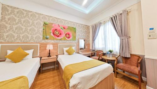 a hotel room with two beds and a desk at Sao Vang Hotel in Bao Loc