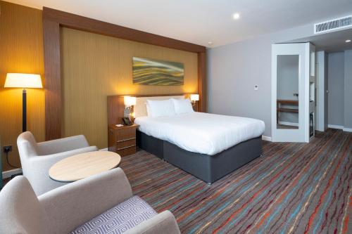a hotel room with a bed and a table and chairs at Holiday Inn Derby Riverlights by IHG in Derby