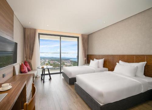 a hotel room with two beds and a large window at Apec Mandala Sun-Condotel Phu Yen in Tuy Hoa