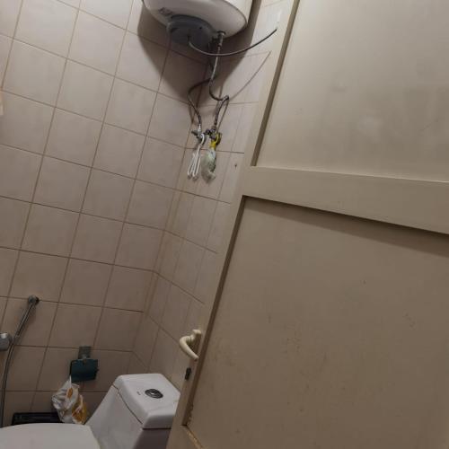 a small bathroom with a toilet and a door at Shared room, Roommate غرفه للمشاركه in Unayzah