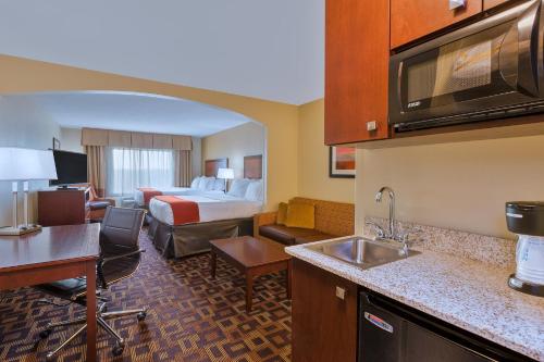 a hotel room with a king bed and a kitchen at Holiday Inn Express Hotel & Suites Salina by IHG in Salina