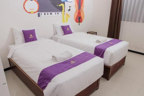 Un pat sau paturi într-o cameră la Votel Nirmala Hotel Malang