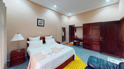 um quarto com uma cama grande e almofadas brancas em Farhyda & Frères Hôtels em Bangangté