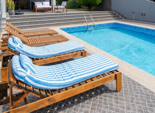 two lounge chairs sitting next to a swimming pool at Luxury Haven: Heated Pool, AC & Sun in Ponta do Sol