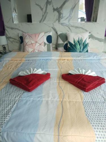 a bed with two red pillows on it at Lee Pool Villa 39 ใกล้ทะเล ส่วนตัว in Jomtien Beach