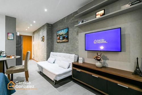 uma sala de estar com um sofá branco e uma televisão de ecrã plano em Novo e Contemporâneo Studio no Centro-RJ/Com Ar no Rio de Janeiro