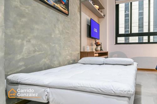 1 dormitorio con 1 cama y TV en la pared en Novo e Contemporâneo Studio no Centro-RJ/Com Ar, en Río de Janeiro