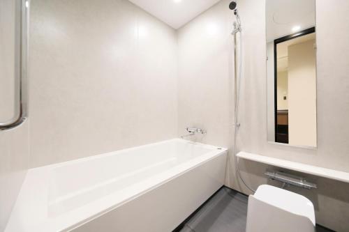 a white bathroom with a tub and a mirror at BLISSTIA Hakone Sengokuhara in Hakone
