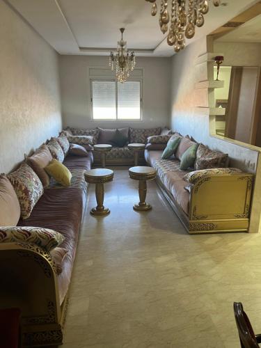 un soggiorno con divano e lampadario pendente di Appartement bien meublé a Skhirat