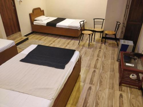 a hotel room with two beds and chairs in it at L OCEAN GUEST HOUSE in Puducherry