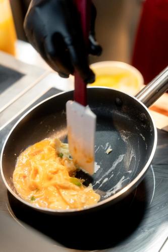 a person is preparing food in a frying pan at Ascott Embassy Sathorn Bangkok in Bangkok