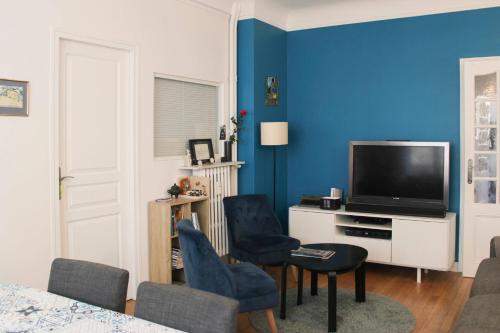 d'un salon avec une télévision et des murs bleus. dans l'établissement Spacious family nest facing Square des Épinette, à Paris