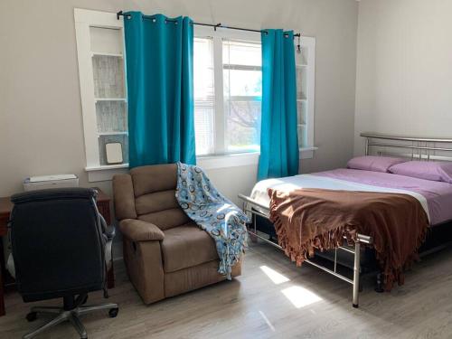 een slaapkamer met een bed, een stoel en een raam bij Chic Home Away From Home! in Bowling Green