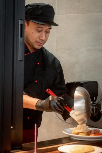 a man is preparing food in a kitchen at Ascott Embassy Sathorn Bangkok in Bangkok