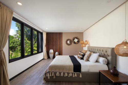 a bedroom with a large bed and large windows at Gorgeous Villa Fizia in Bingin Center in Uluwatu