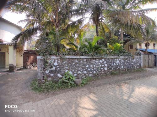 un muro di pietra con palme di fronte a un edificio di Homestay 2 bhk near beach ad Alibaug