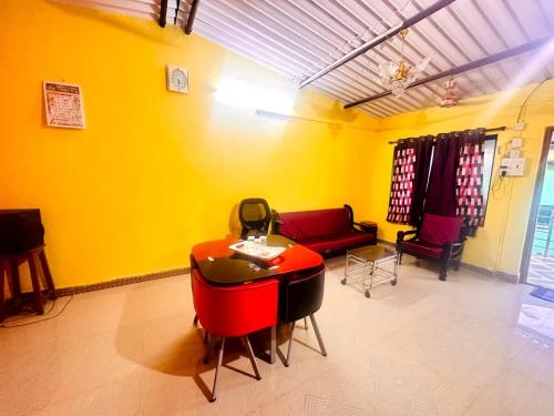 un soggiorno con tavolo rosso e divano di Homestay 2 bhk near beach ad Alibaug