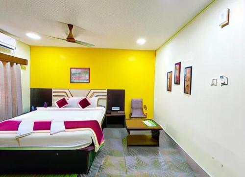 - une chambre avec un grand lit et un mur jaune dans l'établissement Hotel Corel Suit Swimming Pool Hotel, à Purî