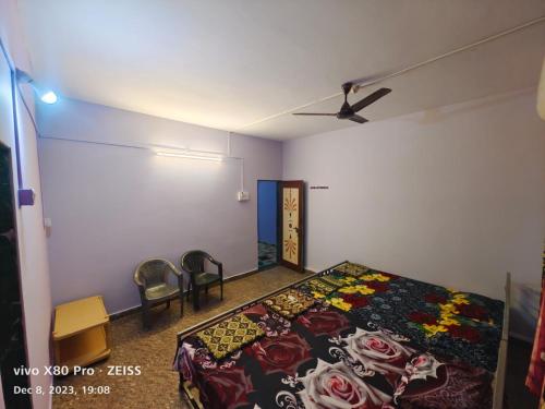 a bedroom with a bed and two chairs at Mahalaxmi home stay tarkarli devbag beach in Bhogwe