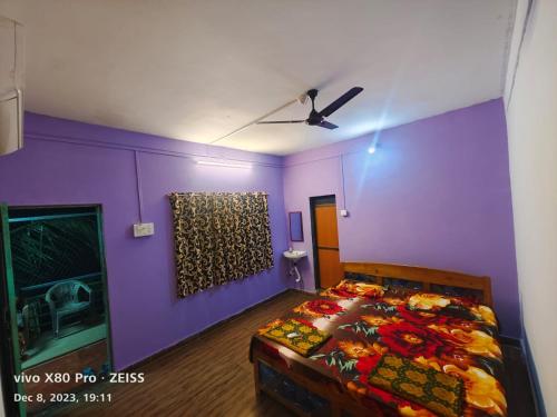 a bedroom with purple walls and a bed at Mahalaxmi home stay tarkarli devbag beach in Bhogwe