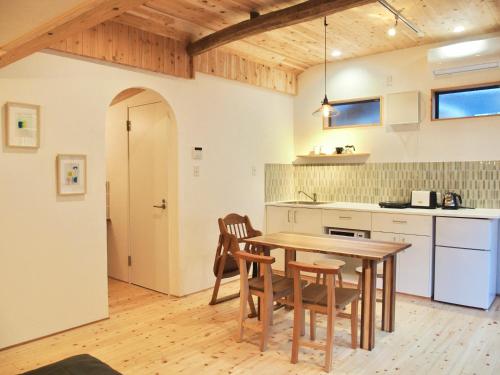 a kitchen with a wooden table and chairs at まるしっぽ邸-Marushippotei-連泊20パーセントOFF!Onsen,BBQ,hammock,national park,home theater in Murautsuri