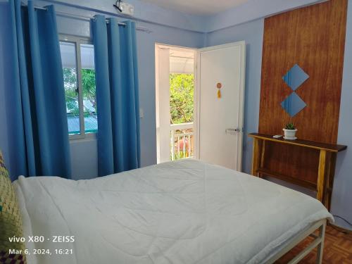 a bedroom with a bed with blue curtains and a window at Ani Marie Guest House in Coron