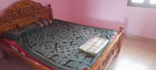 a bed with a wooden frame with a quilt on it at Priya home in Tiruvannāmalai