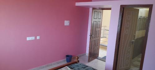 a room with a pink wall and a door at Priya home in Tiruvannāmalai