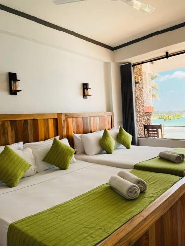 two beds in a room with a view of the ocean at Coral Beach Hotel in Mirissa