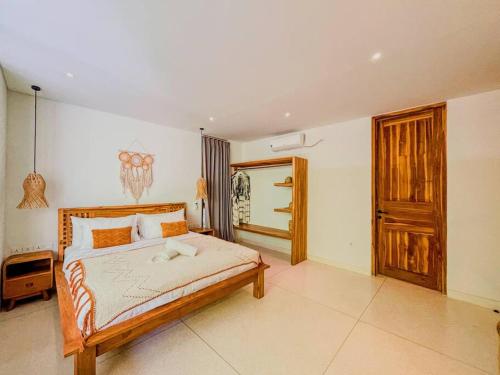 a bedroom with a large bed and a wooden door at Marlaca Villas - Pampita - One bed Kuta Central in Kuta Lombok