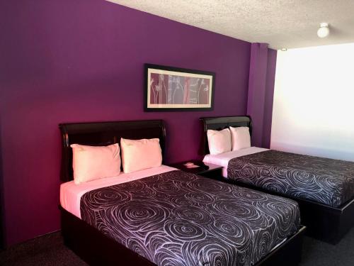 2 camas en una habitación con paredes moradas en HOTEL BUGAMBILIAS, en Ensenada