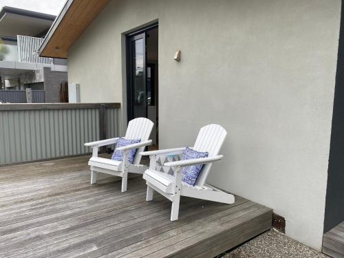 dos sillas blancas sentadas en el porche de una casa en McCrae Beach Front Villa Unit 1, en McCrae