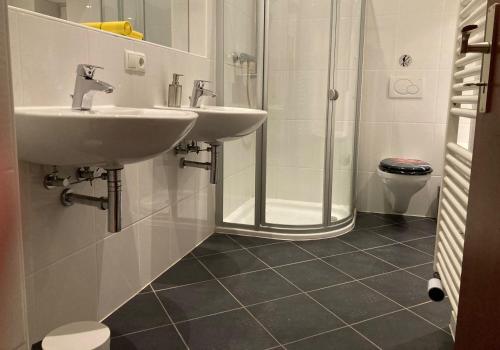 a bathroom with two sinks and a shower at CityChalet Monteur Apartments in Saarbrücken