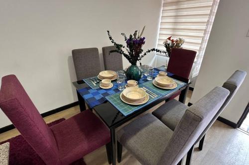 a dining room table with chairs and a vase of flowers at Amplio e impecable apartamento en Cajicá in Cajicá
