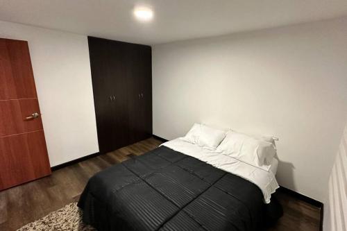 a bedroom with a bed with black sheets and white pillows at Amplio e impecable apartamento en Cajicá in Cajicá