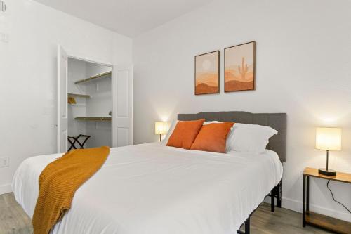 - une chambre avec un grand lit blanc et des oreillers orange dans l'établissement CozySuites Glendale by the stadium with pool 14, à Glendale