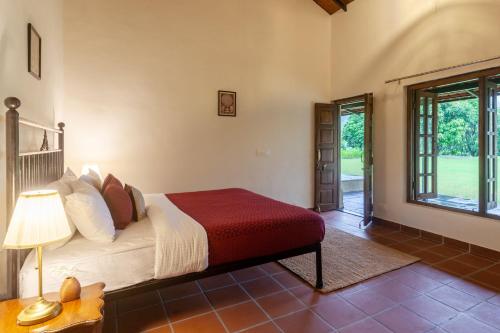 a bedroom with a bed and a table with a lamp at StayVista's Basalt - with Mountain Views, Infinity Pool, Vintage Interiors, and Games Room in Karjat