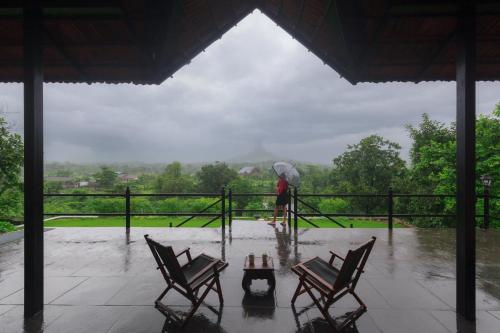 a person walking in the rain with an umbrella at StayVista's Basalt - with Mountain Views, Infinity Pool, Vintage Interiors, and Games Room in Karjat
