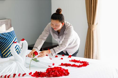 a woman making a bouquet of red roses on a bed at Ratana Angkor Hotel in Siem Reap