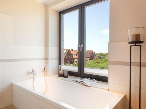ein Bad mit einer Badewanne und einem Fenster in der Unterkunft Reethuus Nord Modern retreat in Juist