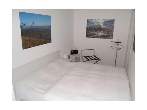 een witte slaapkamer met een bed en een stoel bij "Schnepfenweg" 39 Merchant in Horumersiel