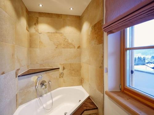 ein Bad mit einer Badewanne und einem Fenster in der Unterkunft Suite Beech Modern retreat in Bad Wiessee