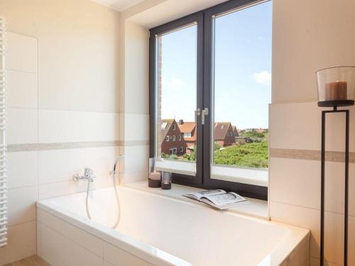ein Bad mit einer Badewanne und einem Fenster in der Unterkunft Reethuus Süd Modern retreat in Juist